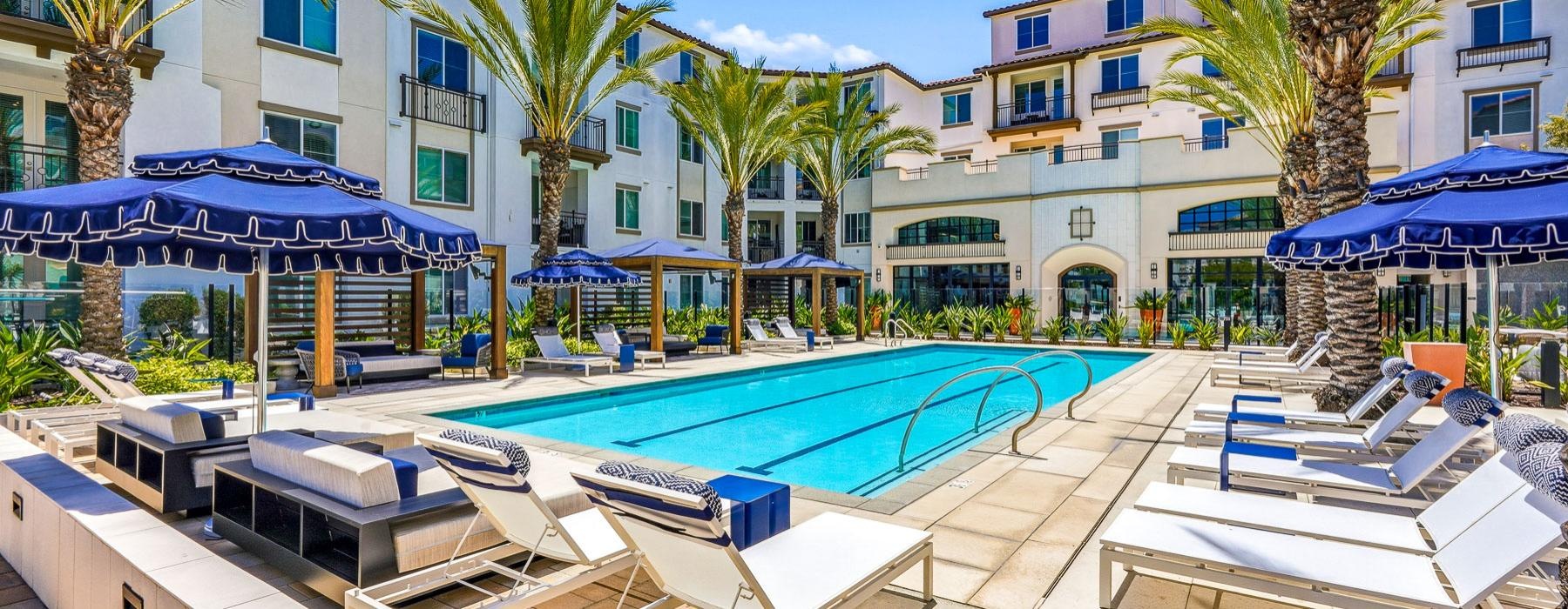 a pool with lounge chairs and umbrellas next to a building